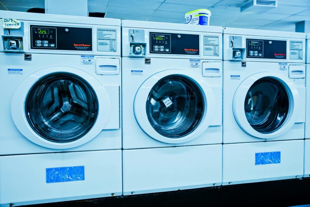 Row of white front-loading washing machines in a laundromat.