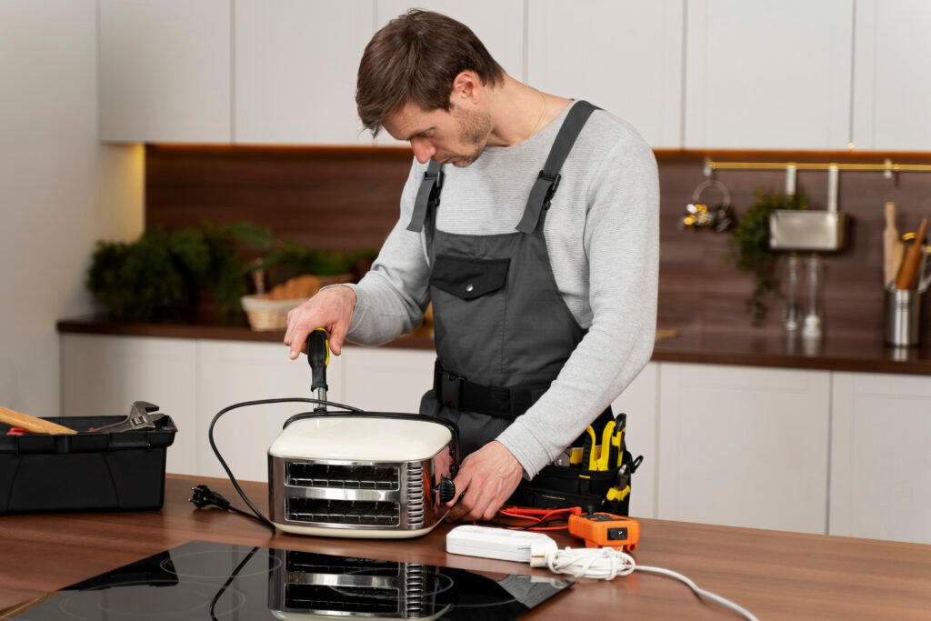 Technician repairing small appliance on kitchen countertop with tools nearby.
